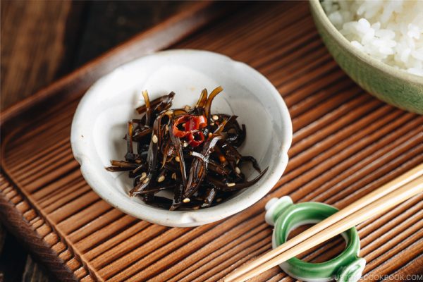 Simmered kombu in a small dish next to a bowl of steamed rice.