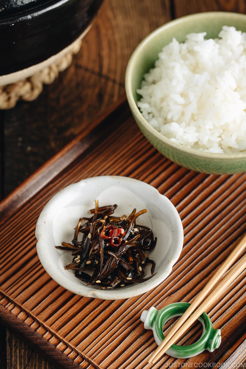 Simmered kombu in a small dish next to a bowl of steamed rice.