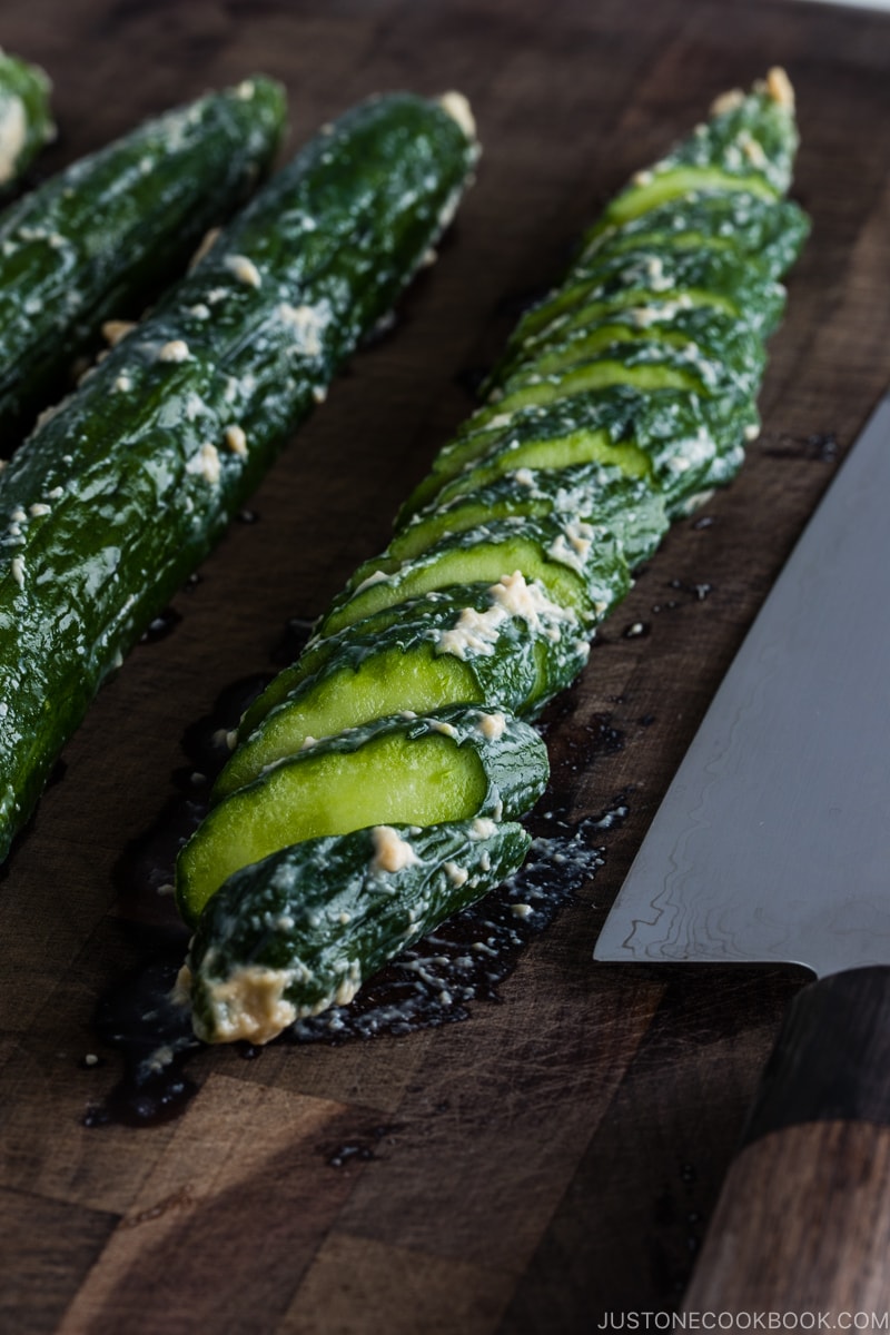 Cucumber Kasuzuke (Sake Lees Pickling) being sliced on a cutting board.