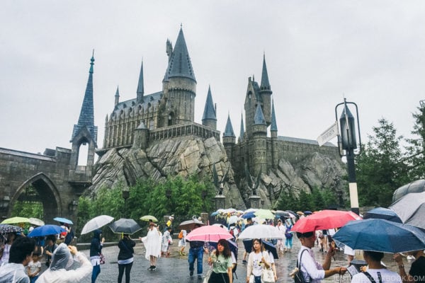 A group of people walking in the rain with an umbrella at Universal Studios Japan