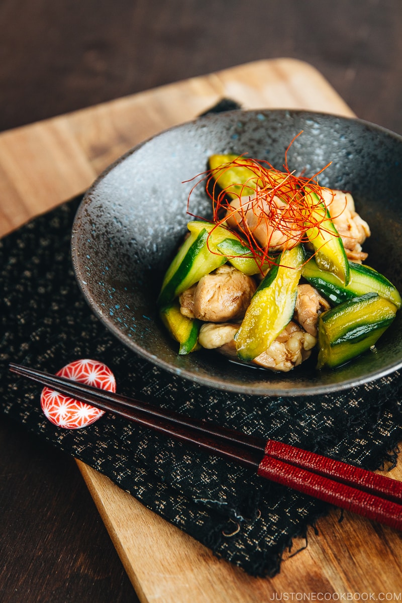 A black ceramic bowl containing Cucumber and Chicken Marinated in Chili Oil.