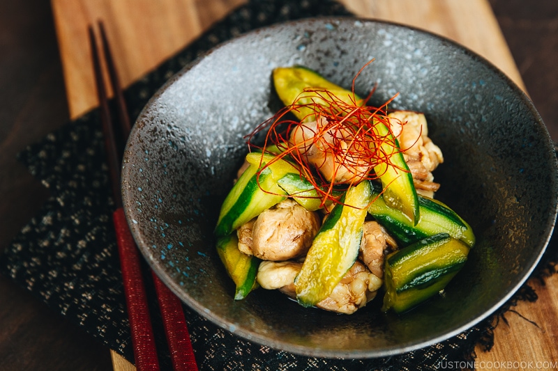 A black ceramic bowl containing Cucumber and Chicken Marinated in Chili Oil.