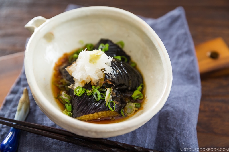 A white ceramic bowl containing eggplant agebitashi.