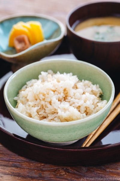 A rice bowl containing ginger rice which is served with miso soup and pickles.