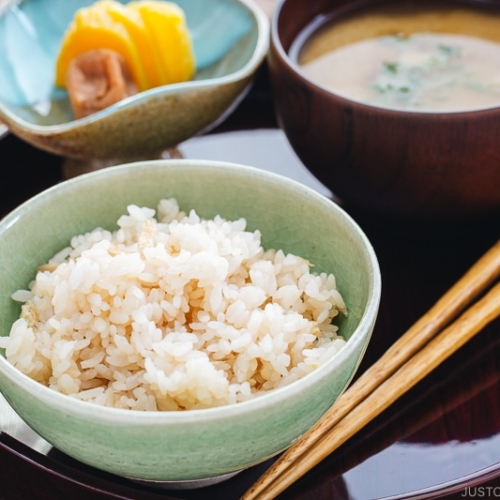 A rice bowl containing ginger rice which is served with miso soup and pickles.