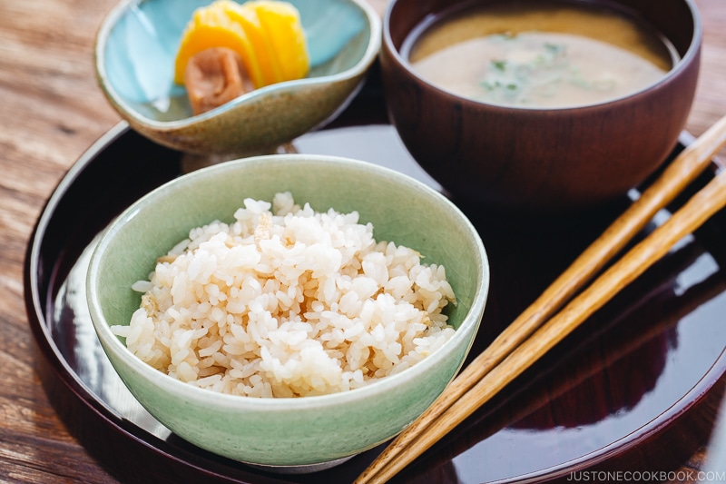 A rice bowl containing ginger rice which is served with miso soup and pickles.