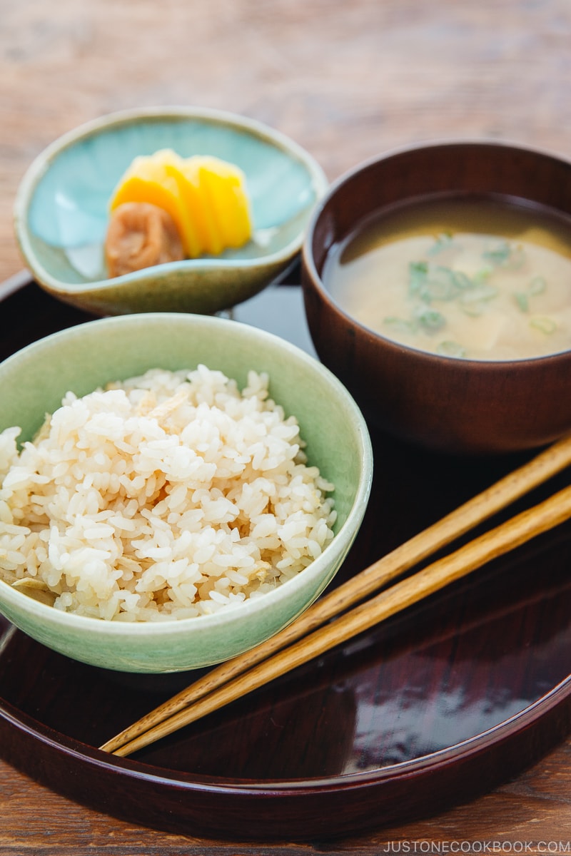 A rice bowl containing ginger rice which is served with miso soup and pickles.