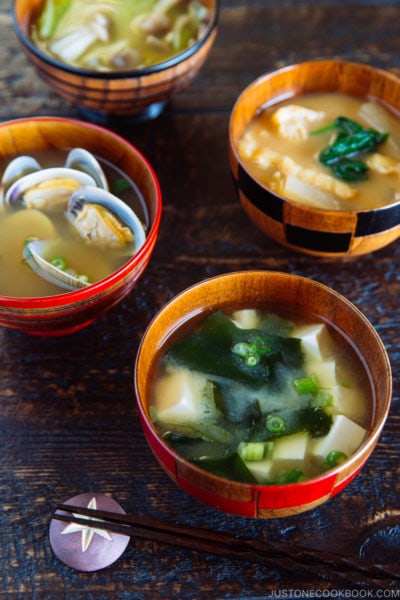 4 wooden miso soup bowls containing different types of miso soup.