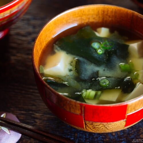 4 wooden miso soup bowls containing different types of miso soup.