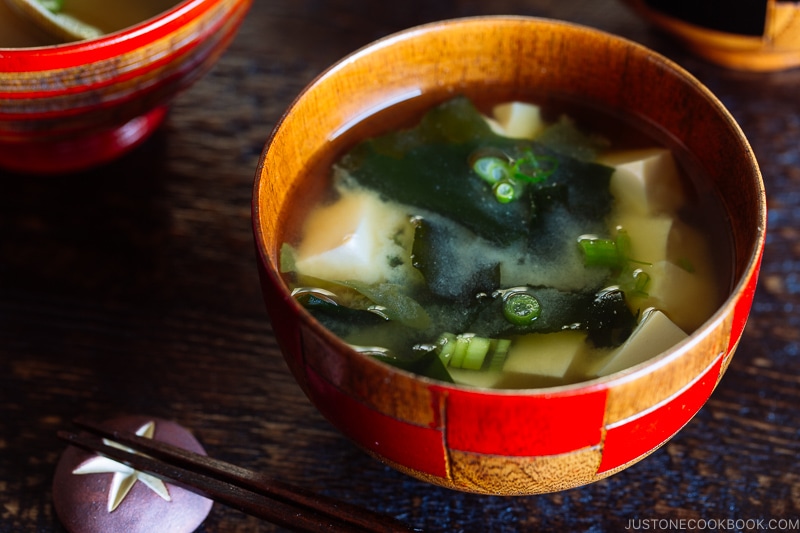 4 wooden miso soup bowls containing different types of miso soup.