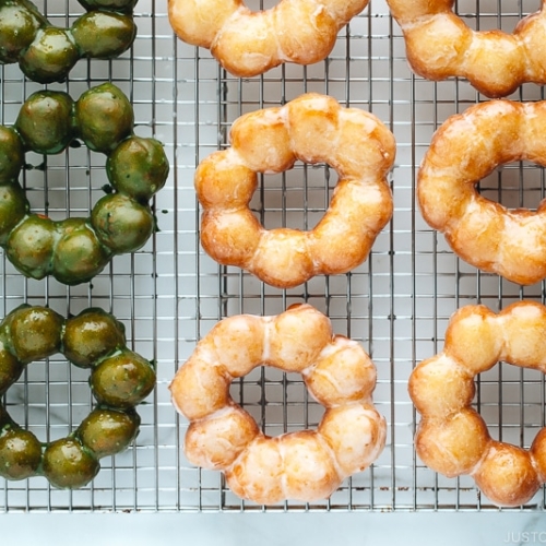 Homemade glazed and matcha glazed pon de ring donuts on a wire rack.