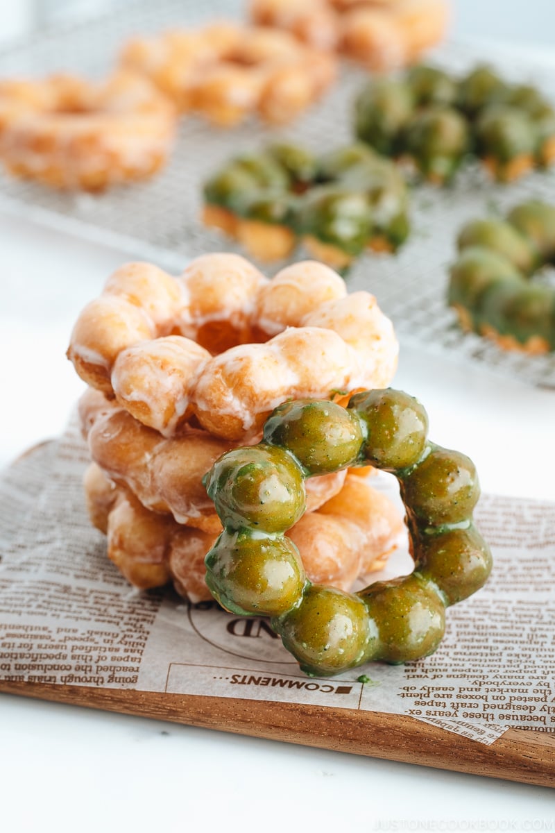 Homemade pon de ring donuts stacked on the wooden board.