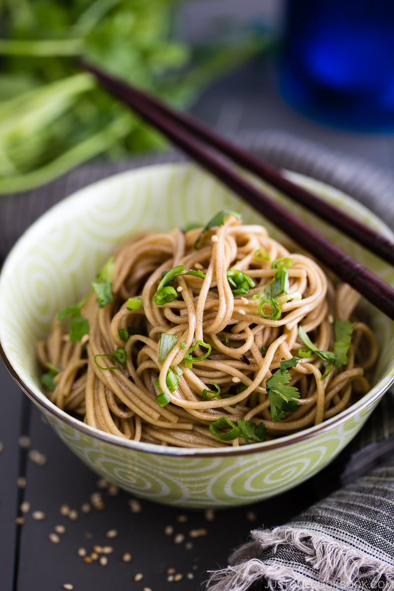 Soba noodle salad with soy honey dressing in a green bowl.