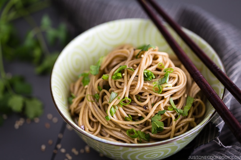 Soba noodle salad with soy honey dressing in a green bowl.