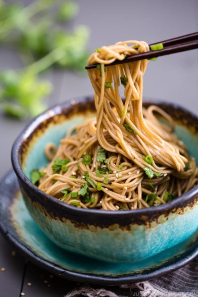 Soba noodle salad with soy honey dressing in a blue bowl.