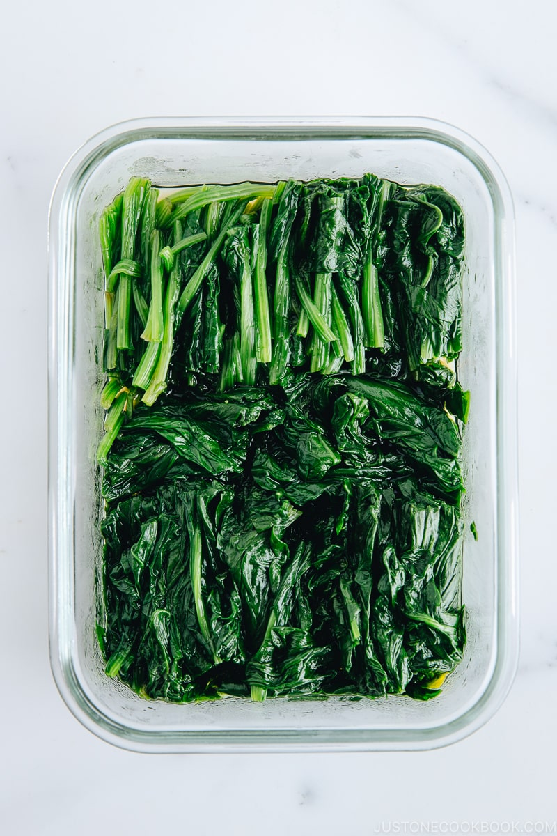 Spinach ohitashi in a glass container.