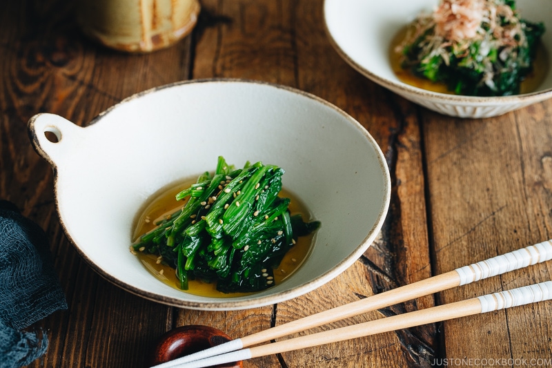 Spinach ohitashi in white ceramic plates.