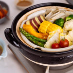 Steamed vegetables on donabe steamer along with dipping sauce.