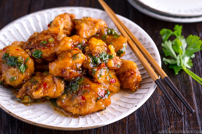 A white plate containing Chicken Karaage with Sweet Chili Sauce and cilantro garnish.