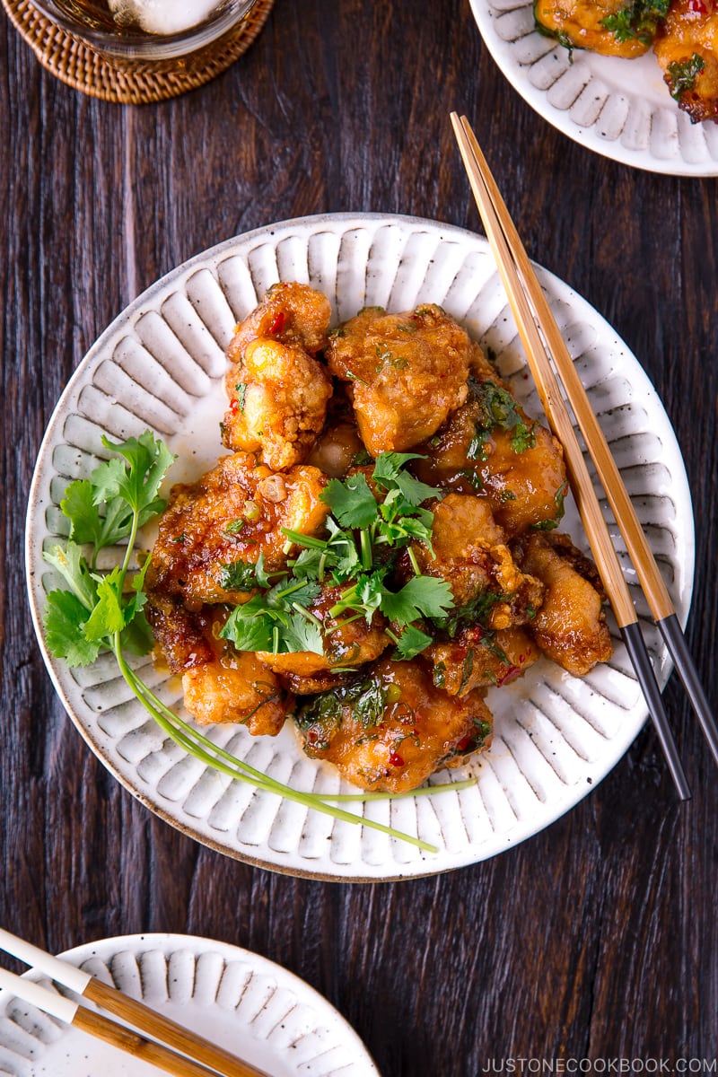 A white plate containing Chicken Karaage with Sweet Chili Sauce and cilantro garnish.