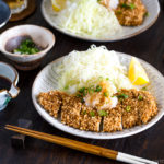 GlutGluten Free Baked Chicken Katsu with cabbage salad and sliced lemon on the plate.