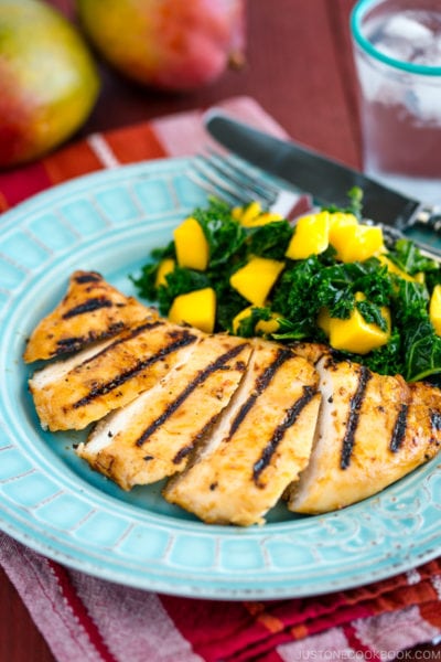 Grilled miso chicken served with Mango Kale Salad on a light blue plate.