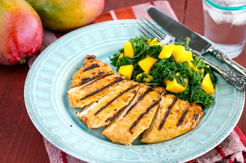 Grilled miso chicken served with Mango Kale Salad on a light blue plate.