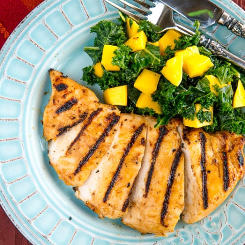 Grilled miso chicken served with Mango Kale Salad on a light blue plate.
