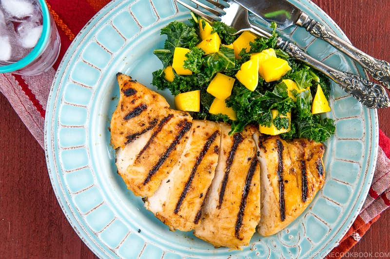 Grilled miso chicken served with Mango Kale Salad on a light blue plate.