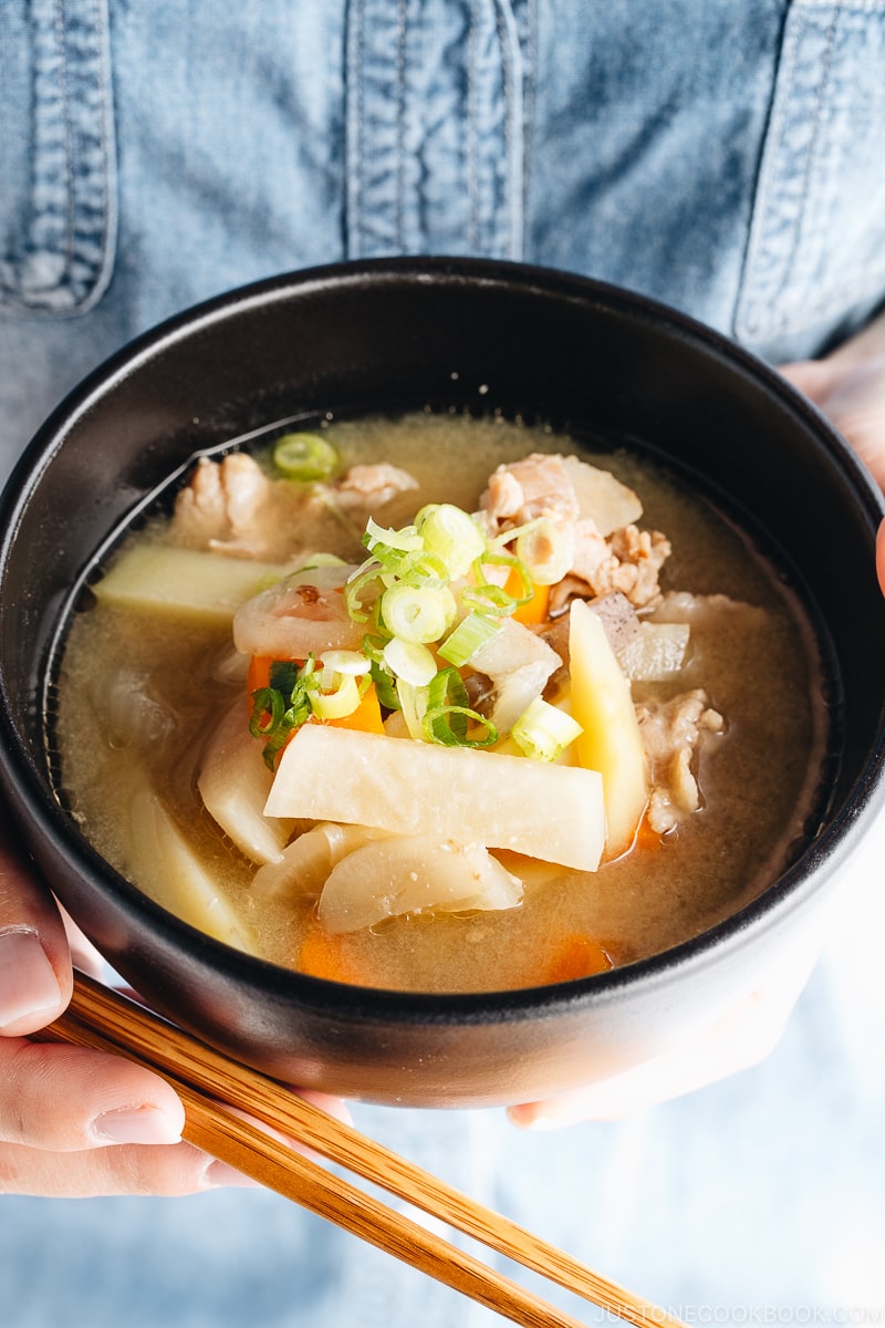 A black bowl containing pork and vegetable miso soup (Tonjiru).