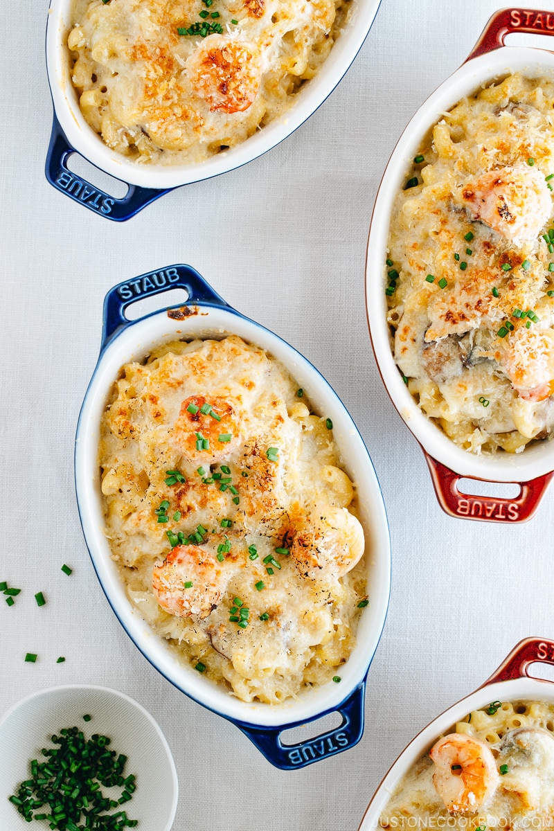 Creamy macaroni gratin in blue and red STAUB gratin dishes.