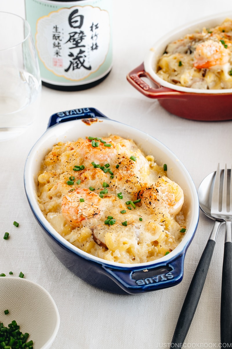 Creamy macaroni gratin in blue and red STAUB gratin dishes.