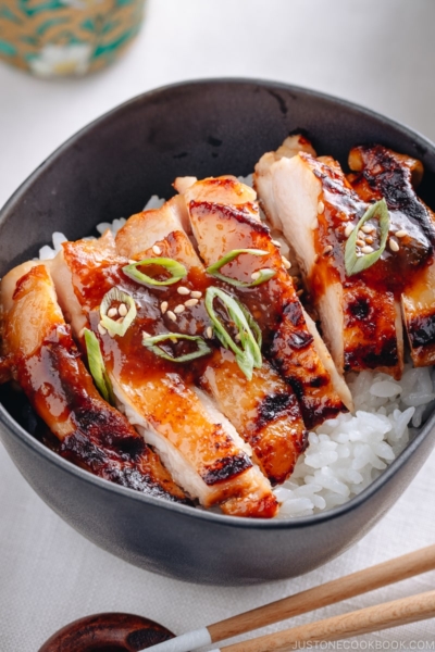 Miso chicken over steamed rice, garnished with sesame seeds and green onion.