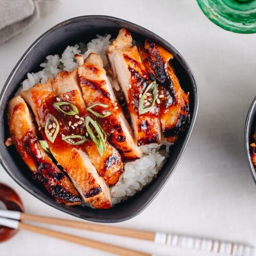 Miso chicken over steamed rice, garnished with sesame seeds and green onion.