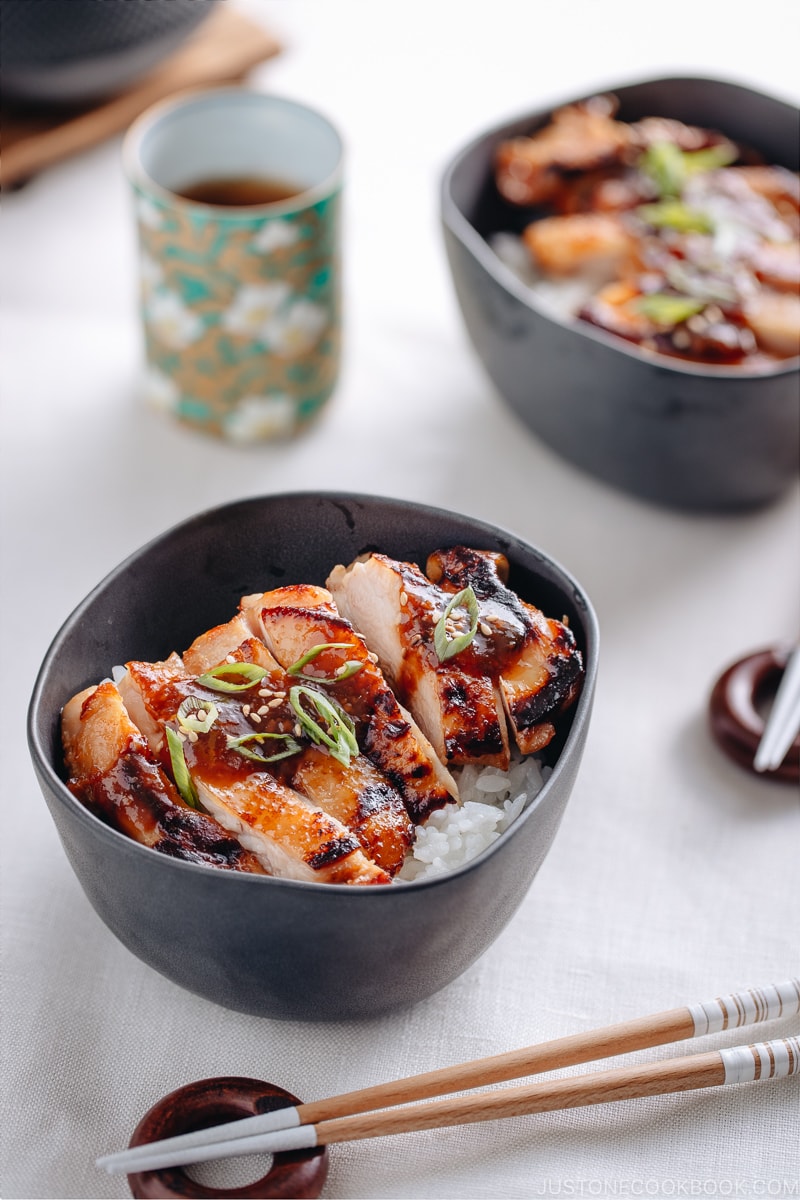 Miso chicken over steamed rice, garnished with sesame seeds and green onion.