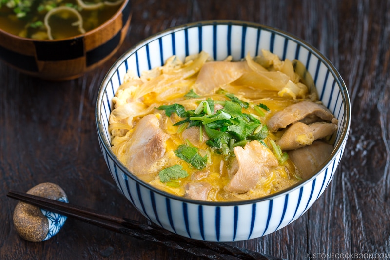 A Japanese blue and white bowl containing Oyakodon (chicken & egg bowl) served with miso soup.