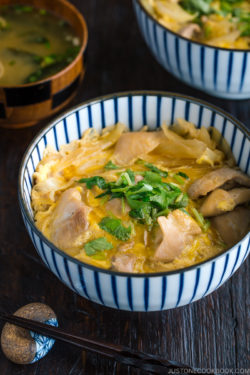 A Japanese blue and white bowl containing Oyakodon (chicken & egg bowl) served with miso soup.