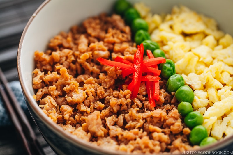 The Japanese bowls containing seasoned ground chicken, scramble eggs, and green veggies.
