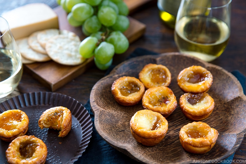 A wooden plate containing cheese tart made with crescent roll and filled with brie cheese and fruit preserves.