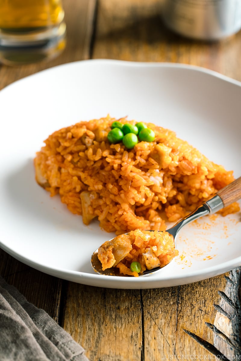 Chicken fried rice served on a white plate, scooped on the spoon.