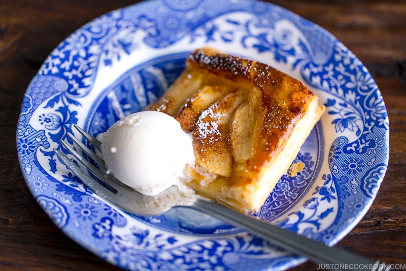 A blue plate containing apple tart cut into pieces and dusted with powder sugar.