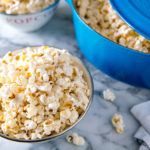 A bowl and Dutch oven containing popcorn with truffle salt seasoning.