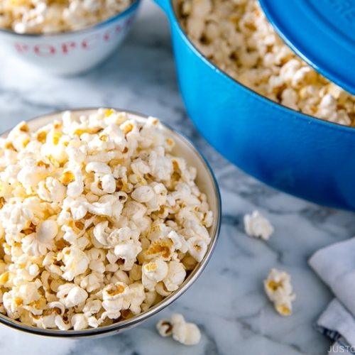 A bowl and Dutch oven containing popcorn with truffle salt seasoning.