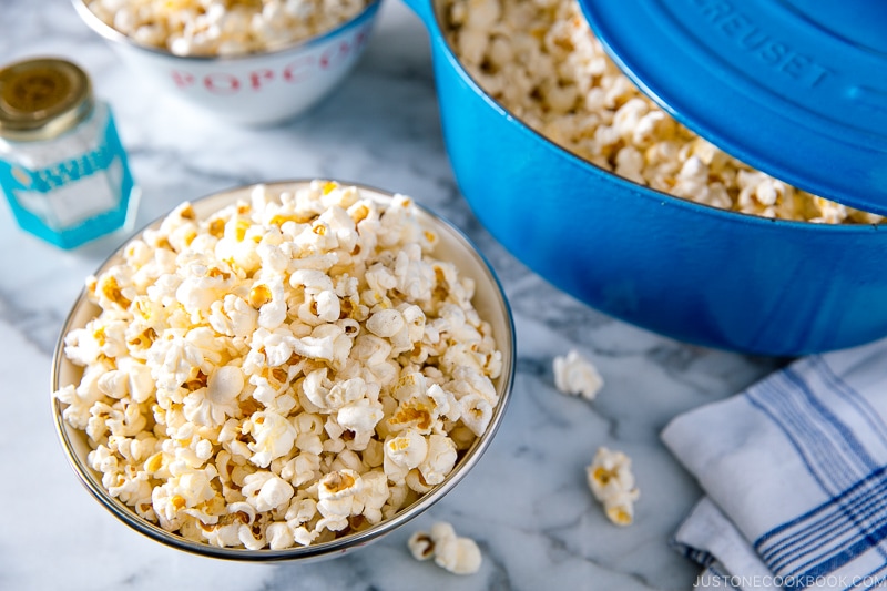 A bowl and Dutch oven containing popcorn with truffle salt seasoning.