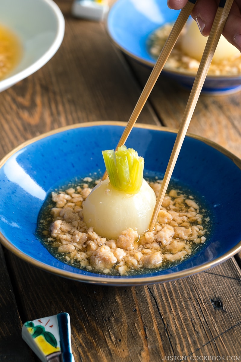 Chopsticks trying to pick up a simmered Japanese turnip.