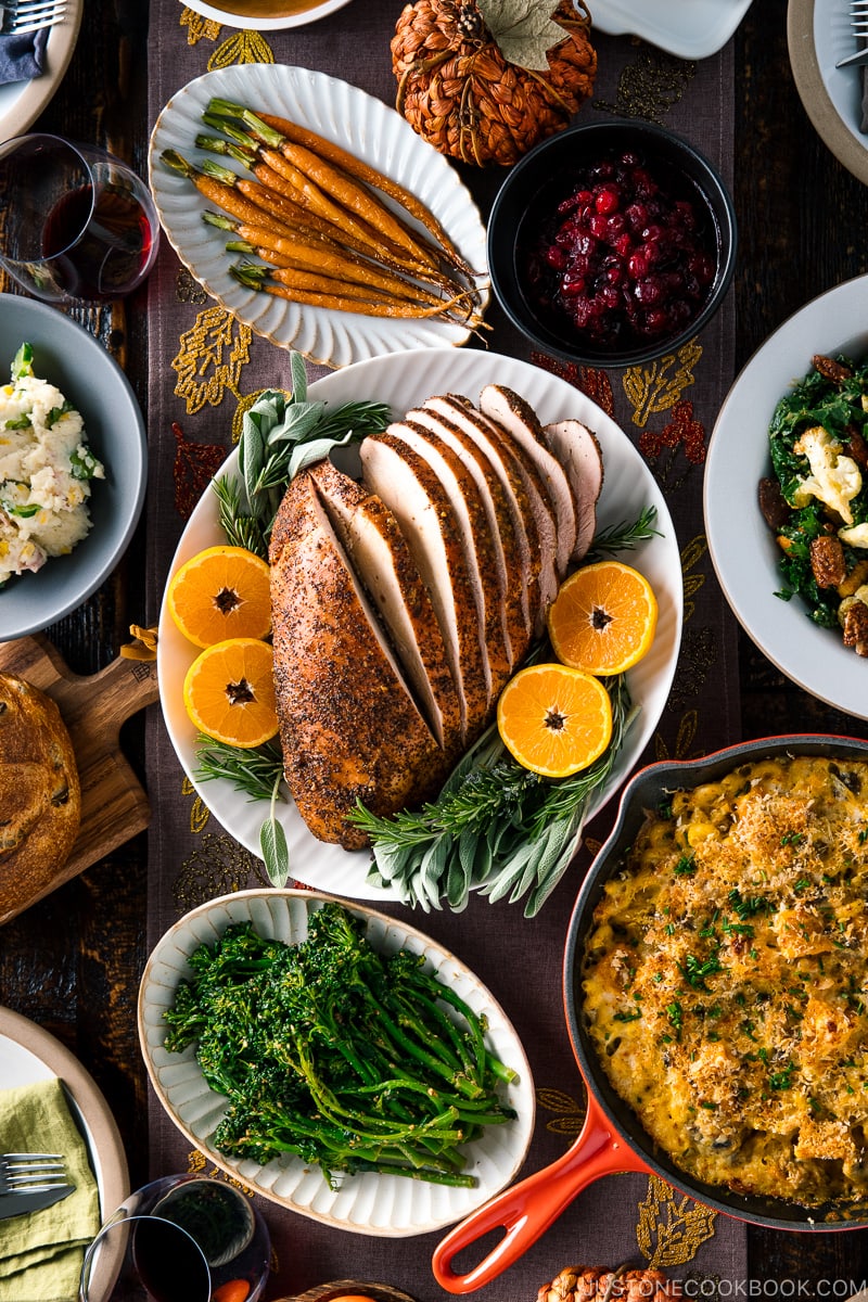 smoked miso butter turkey breast sliced on a white place surrounded by other dishes