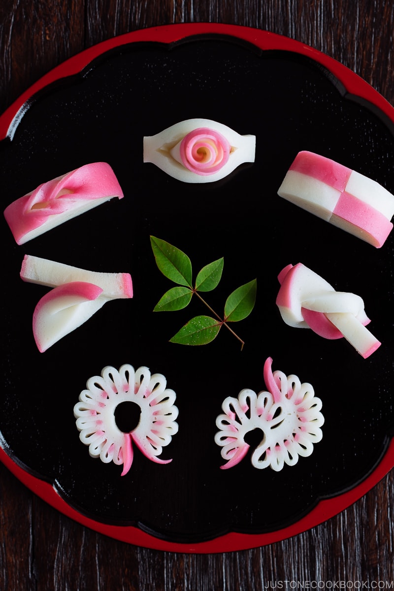 Decorative kamaboko fish cakes on a black and red lacquered board.