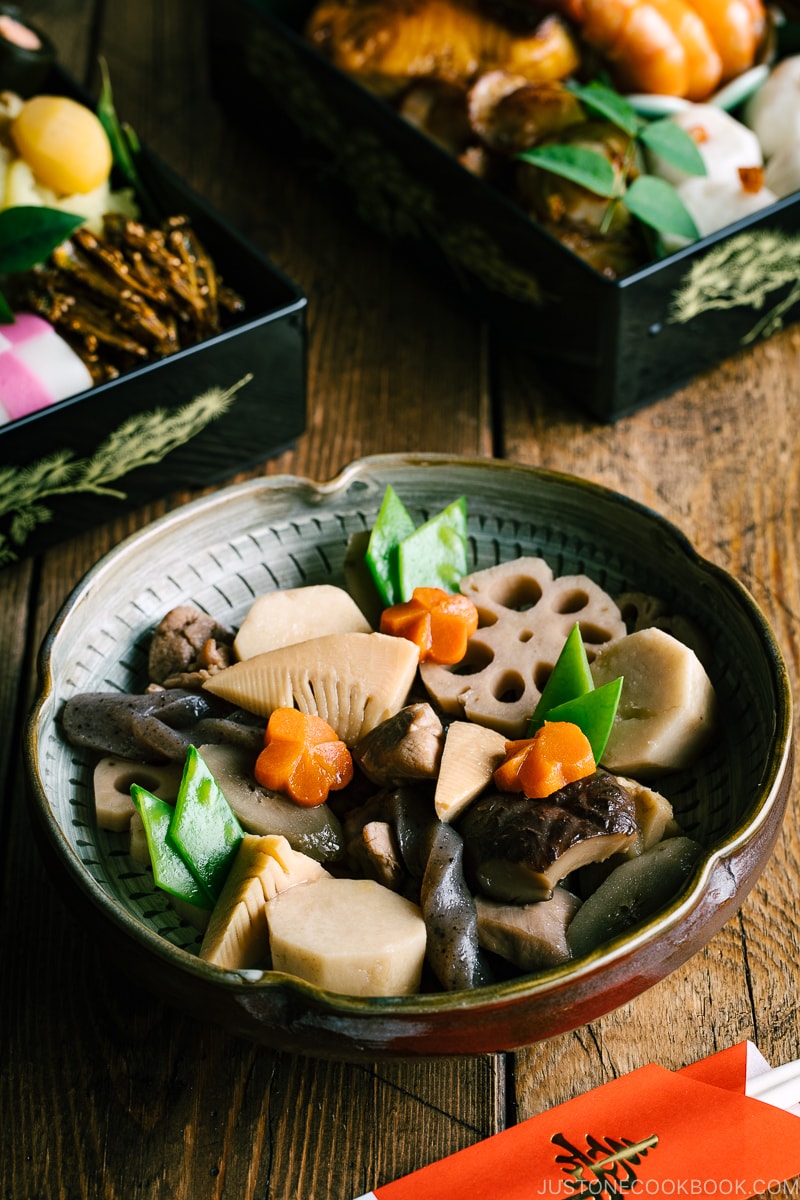 A Japanese ceramic bowl containing simmered chicken and vegetables.