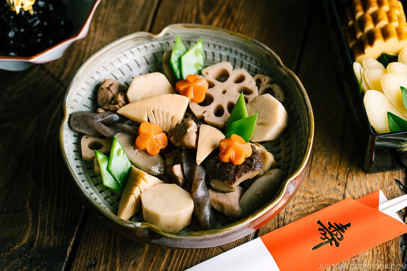 A Japanese ceramic bowl containing simmered chicken and vegetables.