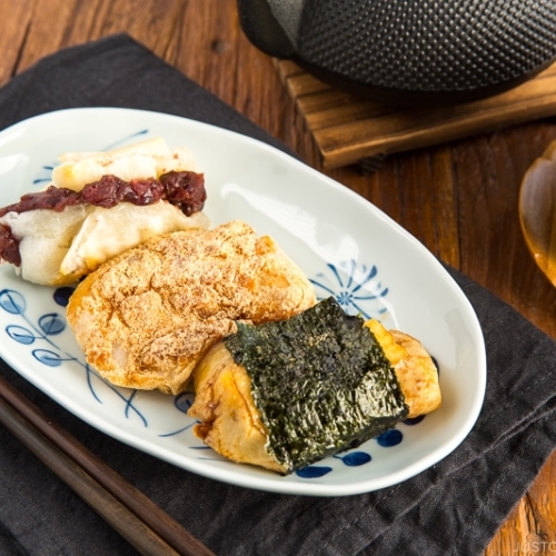 A rectangular plate containing three flavors of mochi (sweet red bean, sweet soybean flour, and soy sauce and nori seaweed).